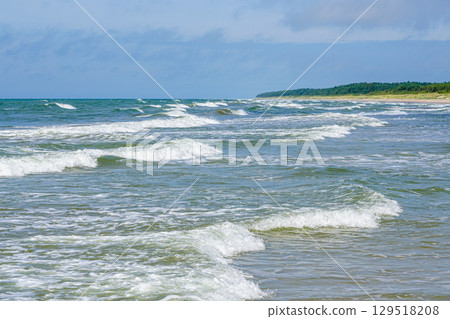 Gentle Waves of the Baltic Sea Meeting the Sandy Shoreline on a Bright Summer Day Gentle Waves of the Baltic Sea Meeting the Sandy Shoreline on a Bright Summer Day 129518208