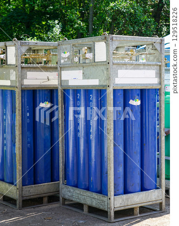 Industrial high-pressure oxygen gas cylinders stored in metal racks for transportation and safety 129518226