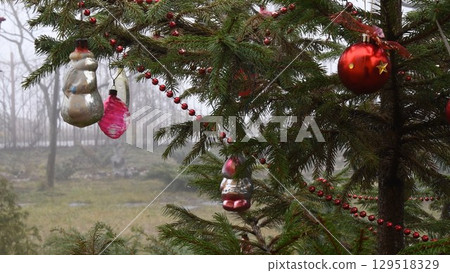 Vintage baubles and red Christmas balls on Christmas tree branches outdoors Vintage baubles and red Christmas balls on Christmas tree branches outdoors 129518329