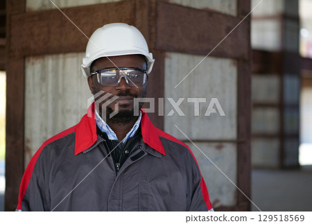 African american workman stands at construction site and looks at camera 129518569