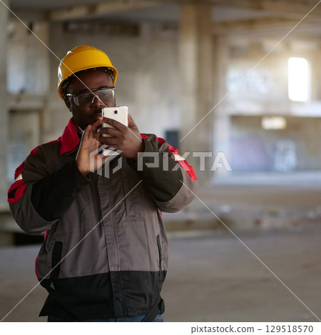African american workman with smartphone at construction site African american workman with smartphone at construction site 129518570