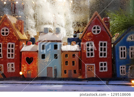 Garland and colorful ceramic houses in the window of a Christmas toy store Garland and colorful ceramic houses in the window of a Christmas toy store 129518606