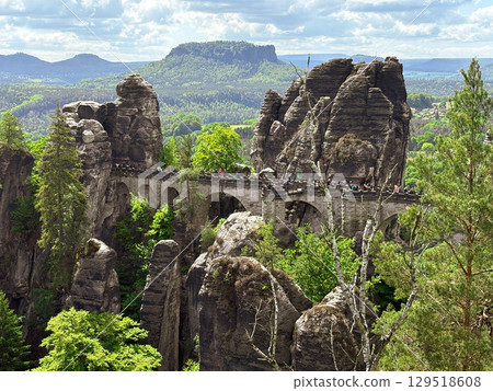May 2025. The Bastei Bridge in Saxon Switzerland is visible through the greenery of the trees. Saxon Switzerland National Park. Editorial May 2025. The Bastei Bridge in Saxon Switzerland is visible through the greenery of the trees. Saxon Switzerland National Park. Editorial 129518608