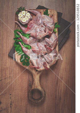 Raw quail meat, on a cutting board, with spices and herbs, top view, 129518652
