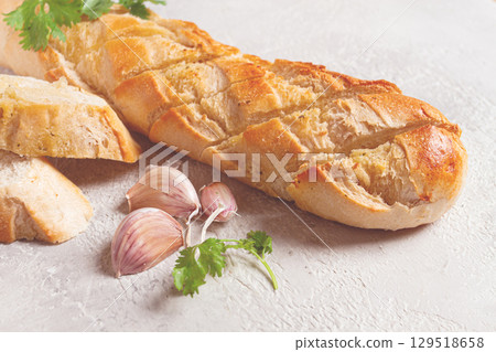 garlic bread,baguette with garlic butter and herbs, on a light table, top view, garlic bread,baguette with garlic butter and herbs, on a light table, top view, 129518658