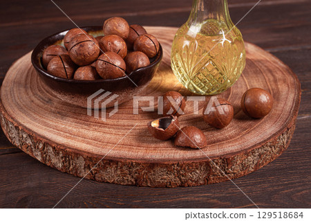 bottle of macadamia oil, on a wooden board, with macadamia nuts, wooden background, selective focus, no people, 129518684