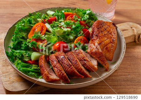 Delicious grilled duck breast served with fresh garden salad and cherry tomatoes at a rustic dining table 129518690