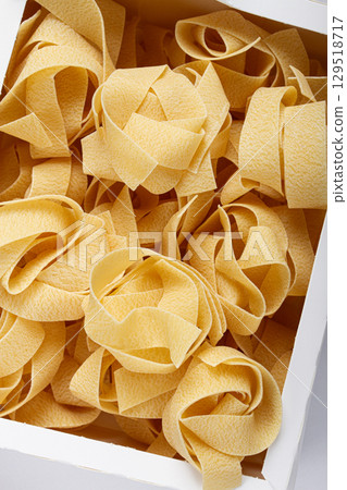 raw pappardelle pasta, pasta nests, in a paper box, top view, no people, raw pappardelle pasta, pasta nests, in a paper box, top view, no people, 129518717