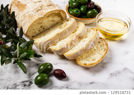 appetizer, sliced ciabatta bread, with olive oil, green olives, Chalkidiki olives, classic Green green olive, on a marble table, top view, no people, appetizer, sliced ciabatta bread, with olive oil, green olives, Chalkidiki olives, classic Green green olive, on a marble table, top view, no people, 129518731