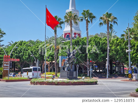 KEMER, TURKEY - JULY 5, 2025 Kemer city centrum, boulevard traffic scene with Ataturk statue on horseback in front of Kemer Saat Kulesi today Cafe Mokka, and red turkish flag winding prominently KEMER, TURKEY - JULY 5, 2025 Kemer city centrum, boulevard traffic scene with Ataturk statue on horseback in front of Kemer Saat Kulesi today Cafe Mokka, and red turkish flag winding prominently 129518855