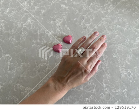 Hand with oval cut diamond ring and pink hearts for Valentine's Day Hand with oval cut diamond ring and pink hearts for Valentine's Day 129519170