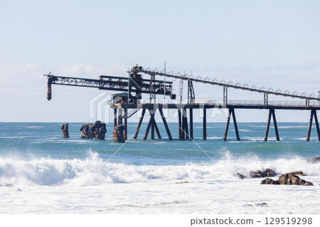 An old and weathered industrial loading jetty and crashing waves An old and weathered industrial loading jetty and crashing waves 129519298