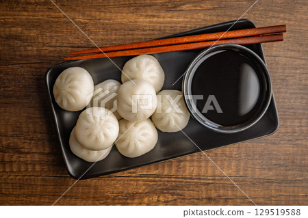 Xiao long bao. Chinese dumplings and soy sauce on wooden table. Top view. 129519588