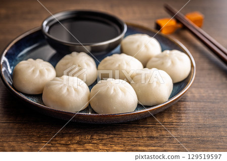 Xiao long bao. Chinese dumplings and soy sauce on plate on wooden table. 129519597