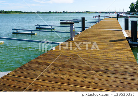 Modern Wooden Marina Pier with Empty Moorings on a Sunny Day at a Peaceful Lakeside Harbor Modern Wooden Marina Pier with Empty Moorings on a Sunny Day at a Peaceful Lakeside Harbor 129520355
