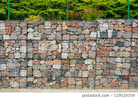Gabion wall with colorful natural stones used for landscaping and erosion control in outdoor space 129520359