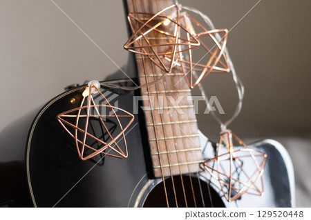 Acoustic guitar decorated Christmas light garland as stars. Christmas carols. Musical instrument. Close up. 129520448