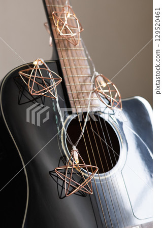 Acoustic guitar decorated Christmas light garland as stars. Christmas carols. Musical instrument. Vertical. Close up. Acoustic guitar decorated Christmas light garland as stars. Christmas carols. Musical instrument. Vertical. Close up. 129520461