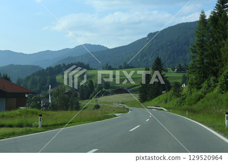 Scenic Countryside Road Surrounded by Lush Green Fields and Rolling Hills Scenic Countryside Road Surrounded by Lush Green Fields and Rolling Hills 129520964