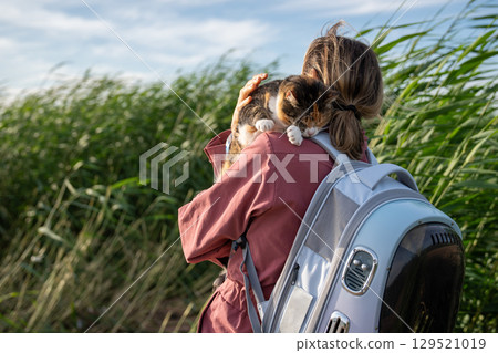 Scared eyes closed cat burrows into woman shoulders, protectively embrace pet in grass field 129521019