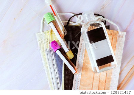 Masks, test tubes, hand sanitizer arranged on surface during health awareness campaign promoting safety practices 129521437