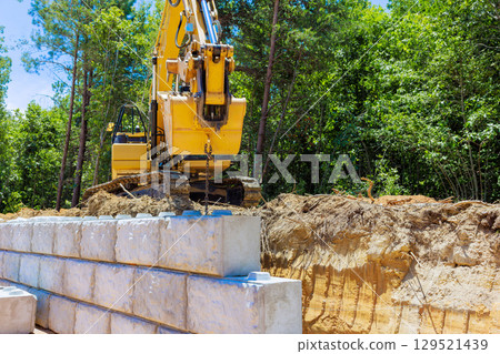 Heavy machinery operates on construction site in forested area during works day hours 129521439