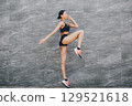 Pretty lady training in a summer city. Brunette doing yoga. Gitl in a sportsuit 129521618