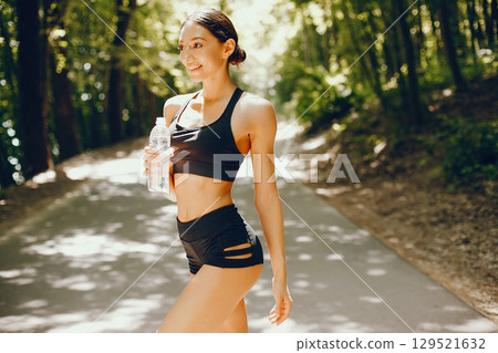 Pretty lady training in a summer park. Brunette with beauty figyre. Girl in a black top 129521632