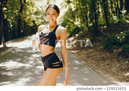 Pretty lady training in a summer park. Brunette with beauty figyre. Girl in a black top 129521633