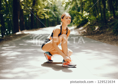 Pretty lady training in a summer park. Brunette with beauty figyre. Girl in a black top Pretty lady training in a summer park. Brunette with beauty figyre. Girl in a black top 129521634