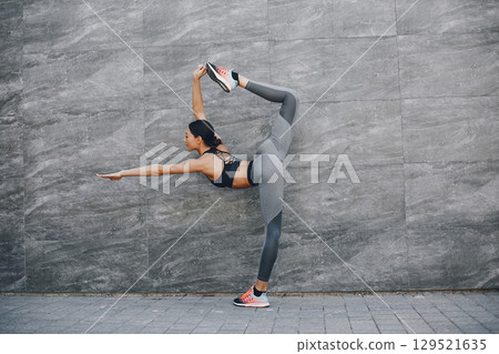 Pretty lady training in a summer city. Brunette doing yoga. Gitl in a sportsuit 129521635