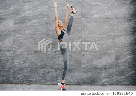 Pretty lady training in a summer city. Brunette doing yoga. Gitl in a sportsuit 129521640