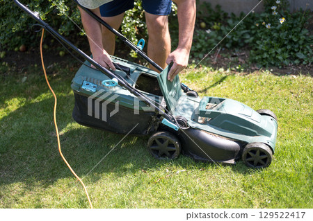 Lawn mowing in the garden, cutting green grass in the summer Lawn mowing in the garden, cutting green grass in the summer 129522417