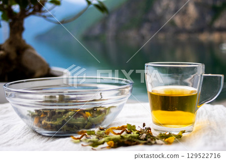 Teacup next to scattered medicinal herbs .Relaxing herbal tea session in nature. Teacup next to scattered medicinal herbs .Relaxing herbal tea session in nature. 129522716