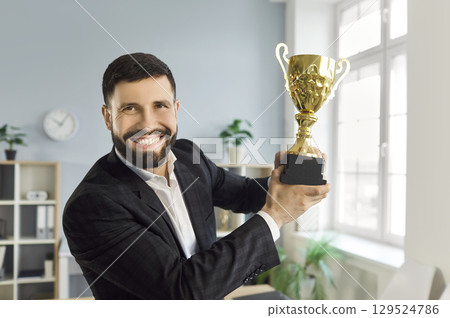 Portrait of happy man employee holding the trophy award for success in business in office. 129524786