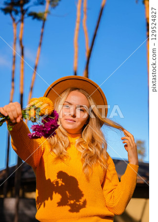 Woman showing into camera Autumn garden colorful flowers. Beautiful autumnal bouquet dahlia chrysanthemum. Red pink orange fall color fall floral background. Flower shop and florist design concept 129524827