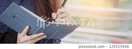 Banner Businesswoman hands writing on notebook meeting agenda in conference room. Banner Woman Hands writing office paper. Female hand holding pencil working Personal Organizer with copy space 129525048