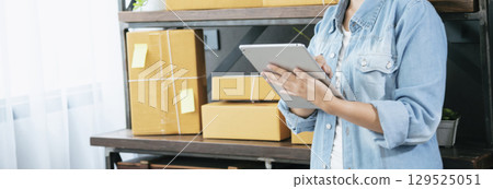 Banner Online seller Close up hands Young asian woman typing laptop keyboard checking online order on stock delivery package. Asian woman startup small business at home office with copy space 129525051