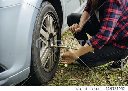 Young women try to change tyre self service. Car problem breakdown. Woman calling mechanic car service technician support fix repair driving. Transportation vehicle accident emergency problem 129525062