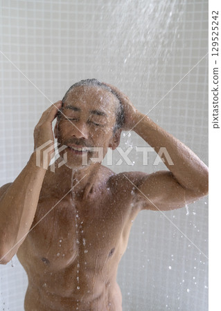 A man in his early 60s taking a shower 129525242