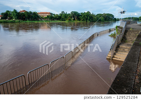 Mae Kok river flood on pedestrian walkway in Chiang Rai province of Thailand during rainy season. This river is the blood line for people of Chiang Rai, started from the hills on boarder of Myanmar. Mae Kok river flood on pedestrian walkway in Chiang Rai province of Thailand during rainy season. This river is the blood line for people of Chiang Rai, started from the hills on boarder of Myanmar. 129525284