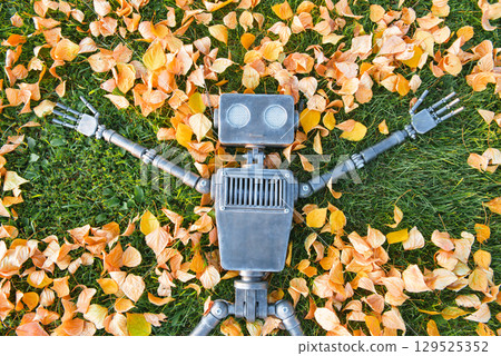 Happy humanoid robot lies on the autumn grass. 129525352