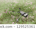 Happy humanoid robot lies on a meadow among wildflowers. Robotic object experiences feelings and emotions. Concept of technology development in the form of artificial intelligence. 129525361