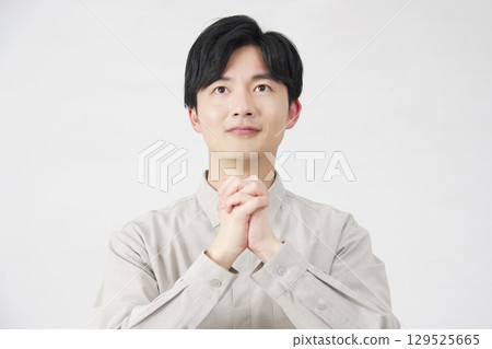 Praying man in his 20s on a white background 129525665