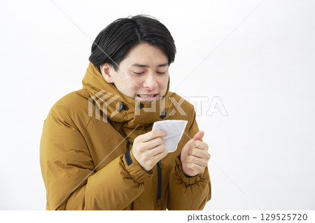 A freezing man holding a hand warmer on a white background 129525720
