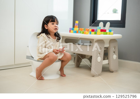 toddler girl learning sit on toilet wc seat at home. child being potty trained 129525796