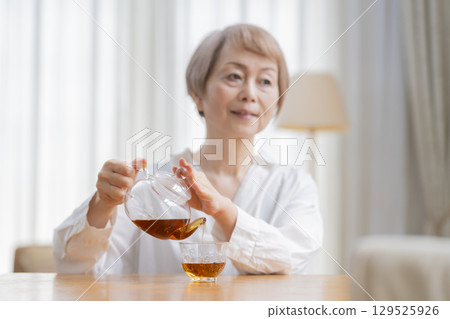餐廳裡倒茶的老年婦女 餐廳裡倒茶的老年婦女 129525926