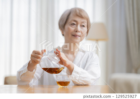 餐廳裡倒茶的老年婦女 餐廳裡倒茶的老年婦女 129525927