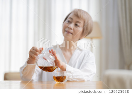 Senior woman pouring tea in the dining room 129525928