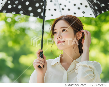 An elegant young woman holding a parasol in the shade 129525992